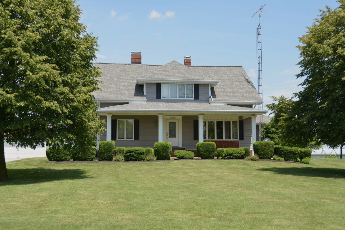 A gray house with a front porch and a green lawn