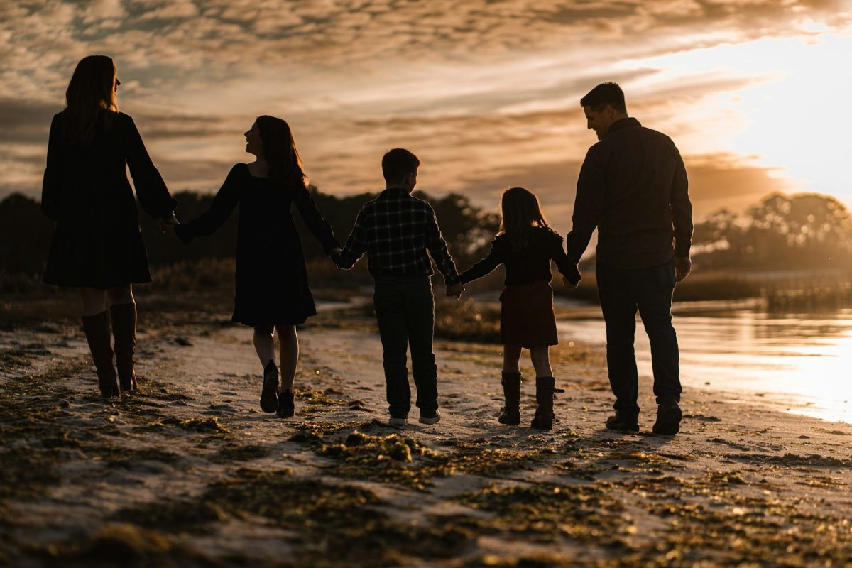 A family walking hand in hand at sunset